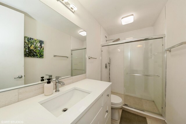 bathroom with vanity, toilet, and a shower with shower door