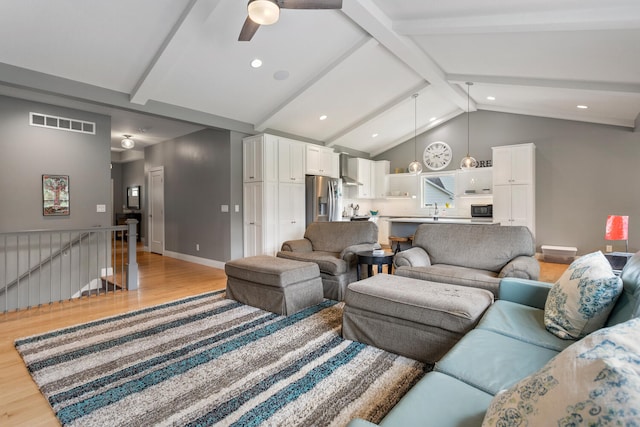 living room featuring lofted ceiling with beams, light hardwood / wood-style floors, ceiling fan, and sink