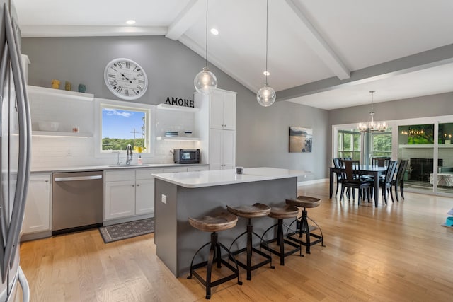 kitchen with white cabinets, decorative backsplash, decorative light fixtures, a kitchen island, and stainless steel appliances