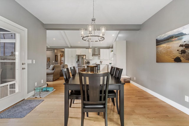 dining space featuring beam ceiling, light hardwood / wood-style floors, and an inviting chandelier