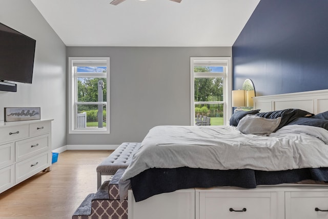 bedroom featuring ceiling fan, light wood-type flooring, and vaulted ceiling