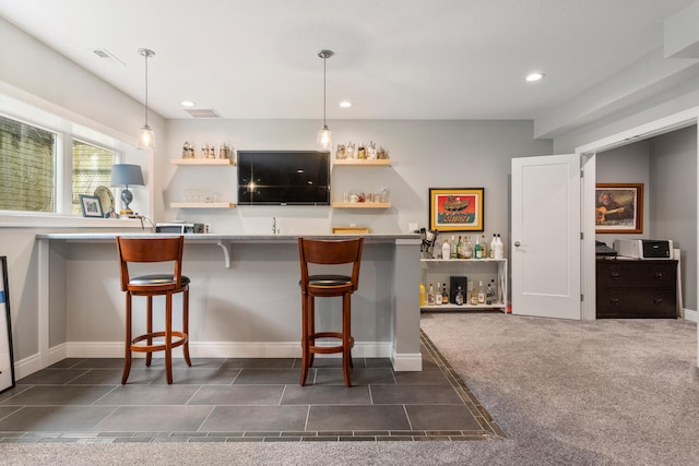 bar with dark colored carpet and pendant lighting