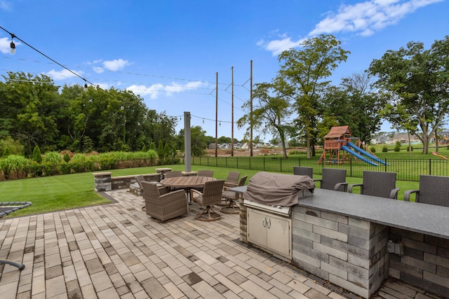 view of patio featuring a playground and exterior kitchen