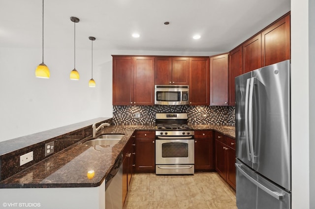 kitchen with kitchen peninsula, appliances with stainless steel finishes, sink, decorative light fixtures, and dark stone countertops