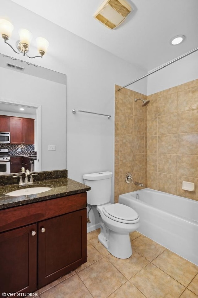 full bathroom featuring vanity, tile patterned floors, tiled shower / bath, decorative backsplash, and toilet