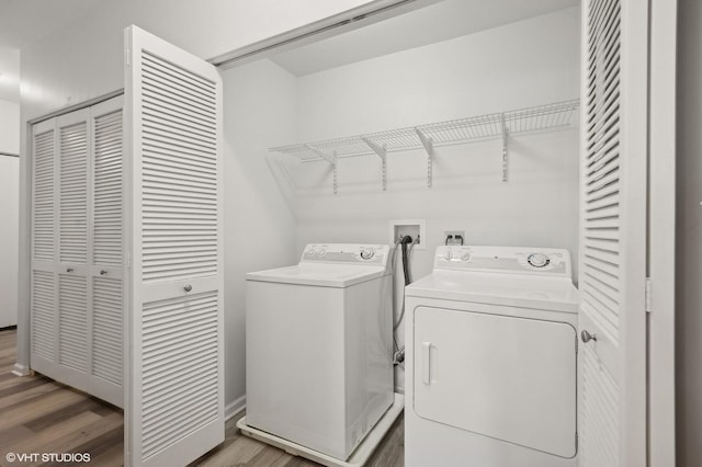 laundry area featuring washing machine and clothes dryer and hardwood / wood-style floors