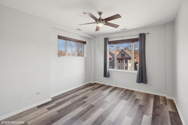 spare room with plenty of natural light, ceiling fan, and wood-type flooring