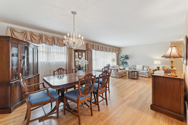 dining space with light hardwood / wood-style floors and a chandelier