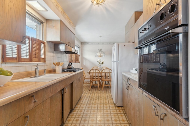 kitchen with a healthy amount of sunlight, hanging light fixtures, white refrigerator, backsplash, and black oven