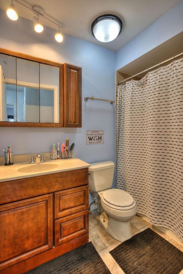 bathroom with track lighting, a shower with curtain, vanity, tile patterned flooring, and toilet