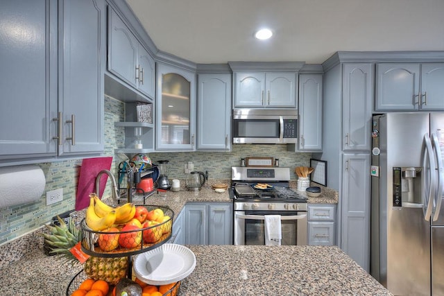 kitchen featuring decorative backsplash, light stone countertops, and appliances with stainless steel finishes