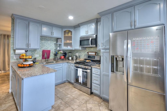 kitchen featuring sink, light stone countertops, tasteful backsplash, light tile patterned flooring, and stainless steel appliances