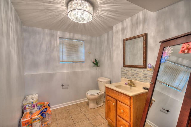 bathroom with toilet, tile patterned flooring, vanity, and an inviting chandelier