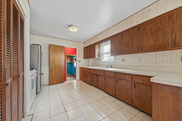 kitchen featuring stainless steel refrigerator, sink, and light tile patterned floors