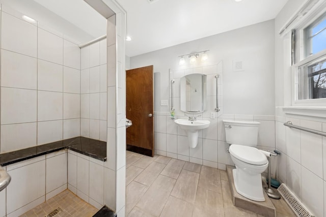 bathroom featuring a shower, tile walls, and toilet