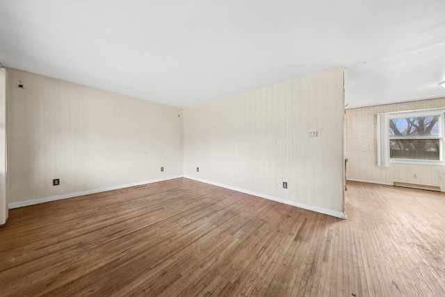 spare room featuring baseboard heating and wood-type flooring