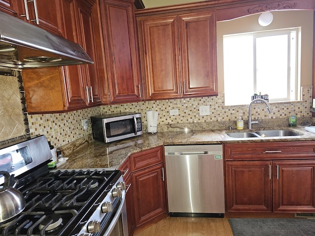 kitchen featuring sink, light hardwood / wood-style flooring, appliances with stainless steel finishes, dark stone countertops, and backsplash