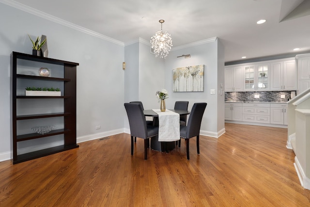 dining room with light hardwood / wood-style floors, crown molding, and a chandelier