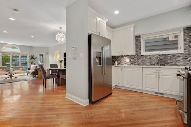 kitchen featuring backsplash, white cabinets, stainless steel appliances, and hanging light fixtures