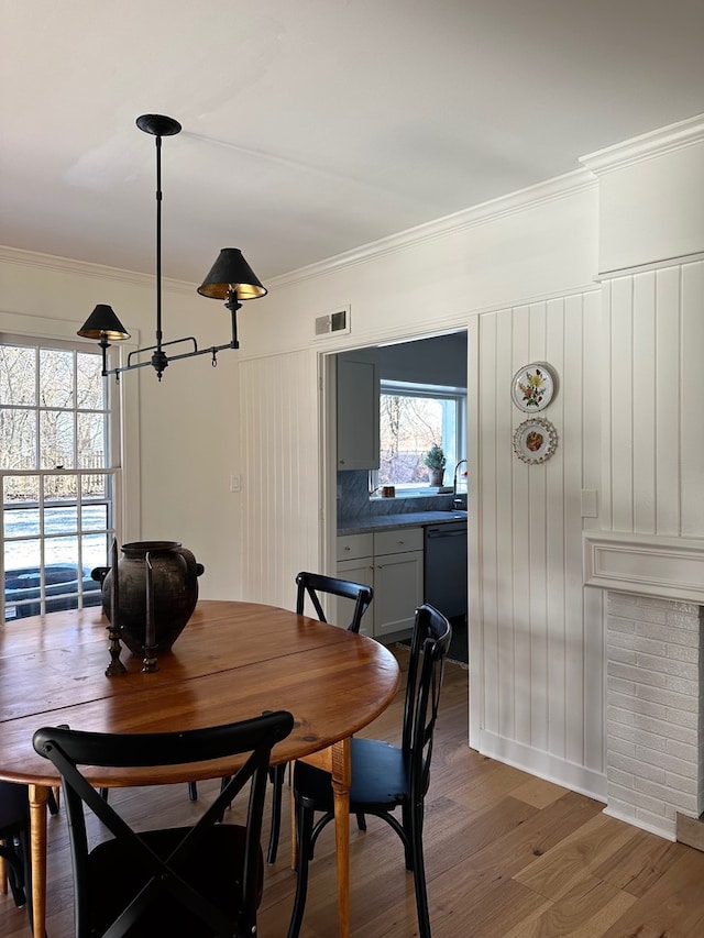 dining space featuring wood-type flooring, plenty of natural light, and crown molding