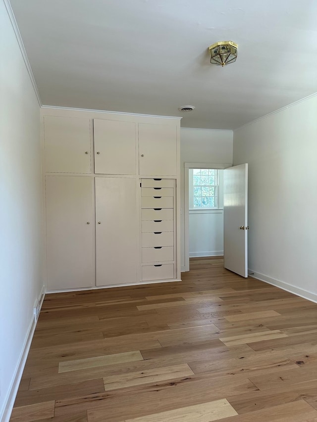 unfurnished bedroom featuring light wood-type flooring, a closet, and crown molding