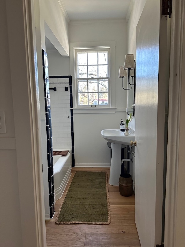 bathroom with shower / bathing tub combination, wood-type flooring, crown molding, and sink