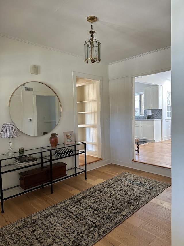 interior space featuring ornamental molding, light hardwood / wood-style floors, and a notable chandelier