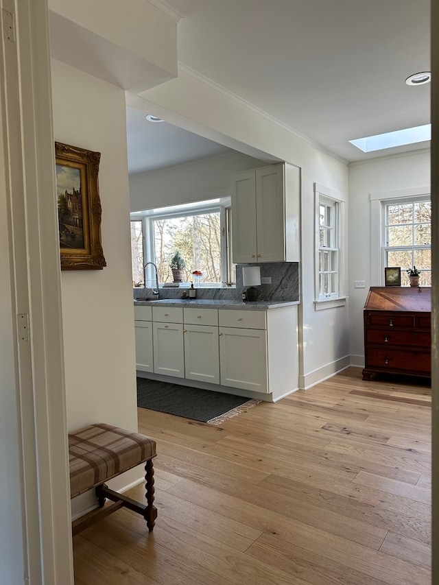 kitchen with tasteful backsplash, a skylight, a wealth of natural light, and light hardwood / wood-style flooring