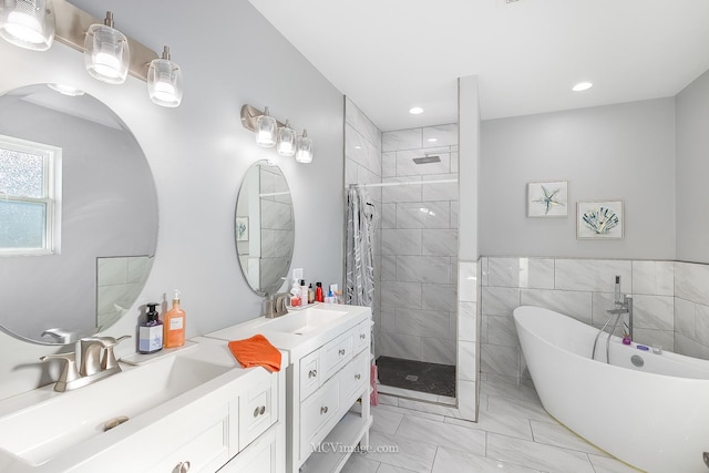 bathroom featuring plus walk in shower, vanity, and tile walls