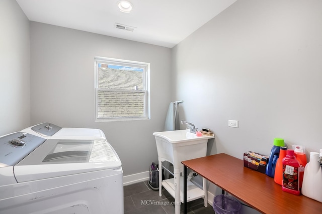 clothes washing area featuring separate washer and dryer and dark tile patterned flooring