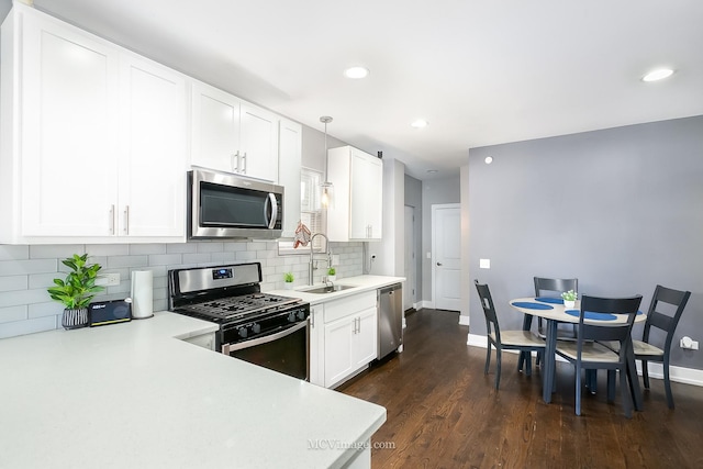 kitchen featuring dark hardwood / wood-style flooring, stainless steel appliances, sink, white cabinets, and hanging light fixtures