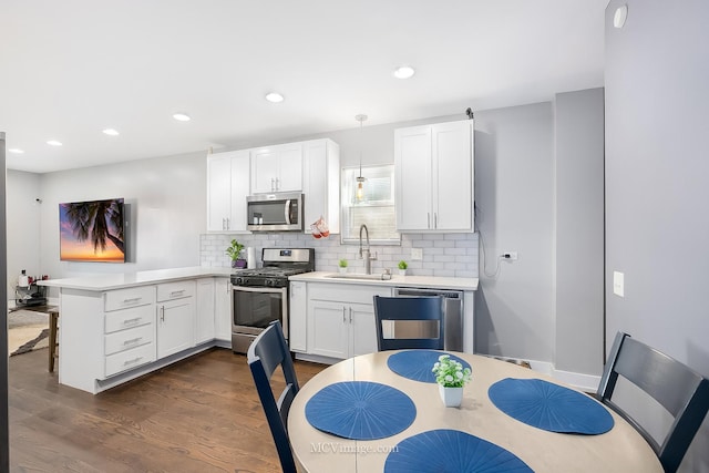 kitchen featuring backsplash, sink, hanging light fixtures, kitchen peninsula, and stainless steel appliances