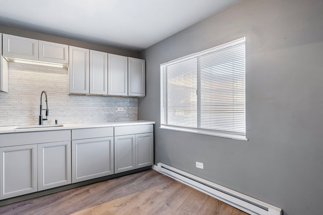 kitchen featuring decorative backsplash, light hardwood / wood-style flooring, sink, and a baseboard radiator