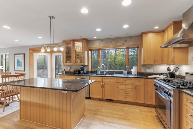 kitchen featuring a breakfast bar, a center island, sink, wall chimney exhaust hood, and stainless steel appliances