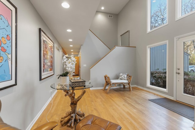 entryway with a towering ceiling and light wood-type flooring