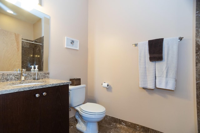 bathroom with a tile shower, vanity, and toilet