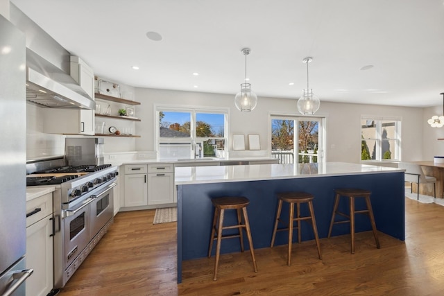 kitchen with a breakfast bar, stainless steel appliances, a kitchen island, pendant lighting, and white cabinetry