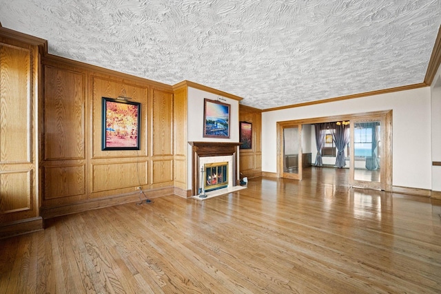 unfurnished living room with wood-type flooring, crown molding, and a premium fireplace