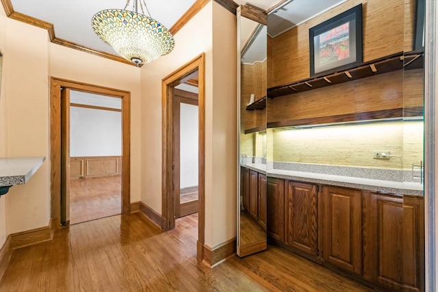 bar featuring crown molding, an inviting chandelier, hanging light fixtures, and wood-type flooring