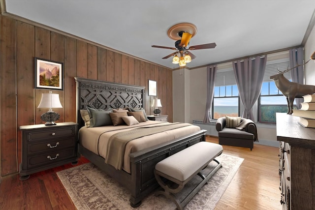 bedroom with radiator, light wood-type flooring, ceiling fan, and ornamental molding