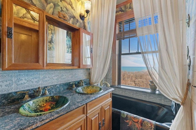 bathroom with decorative backsplash, vanity, and a tub to relax in