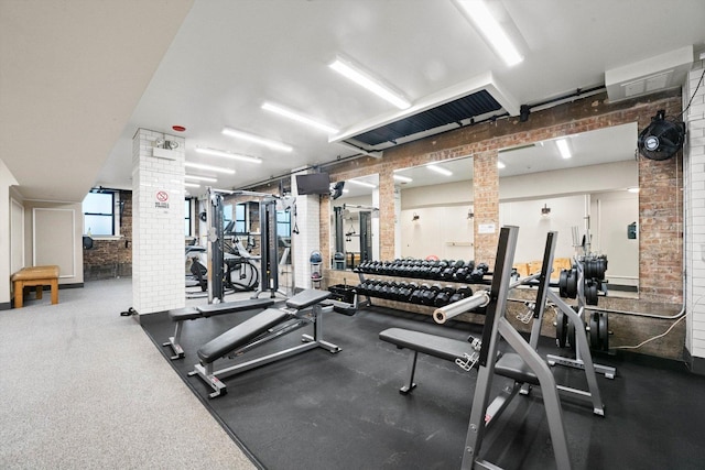 exercise room with ornate columns and brick wall