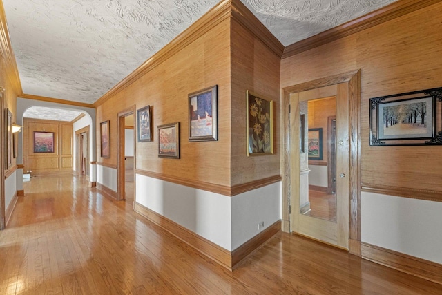 corridor with a textured ceiling, hardwood / wood-style flooring, and crown molding