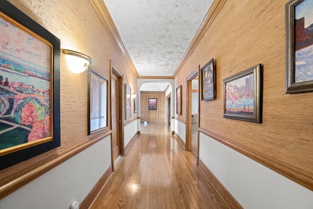 corridor with wood-type flooring, a textured ceiling, and ornamental molding