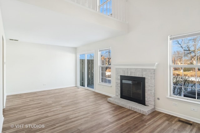 unfurnished living room with light hardwood / wood-style floors and a brick fireplace