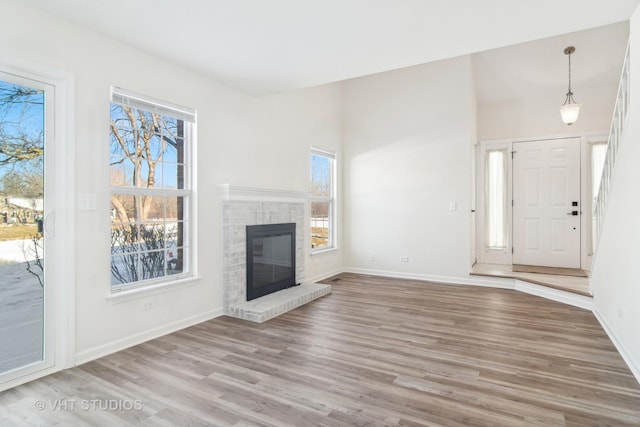 unfurnished living room with light hardwood / wood-style floors, a healthy amount of sunlight, and a fireplace