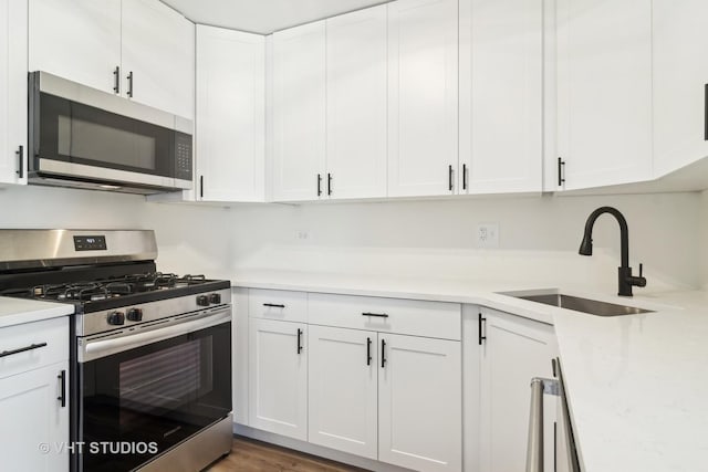 kitchen with sink, dark hardwood / wood-style flooring, white cabinetry, and appliances with stainless steel finishes