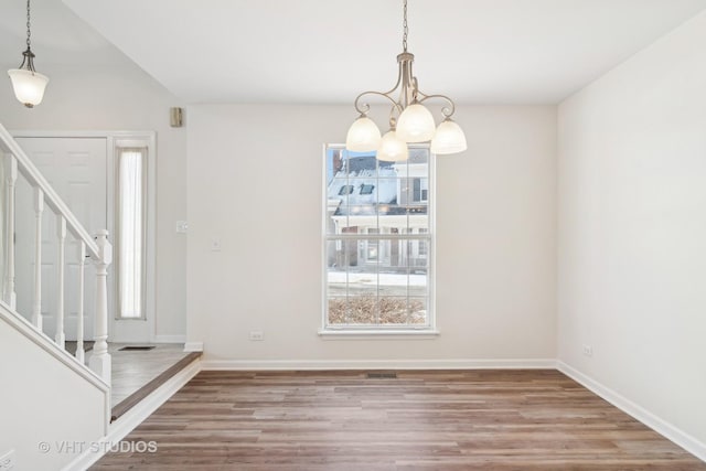 unfurnished dining area featuring a notable chandelier, a healthy amount of sunlight, and wood-type flooring