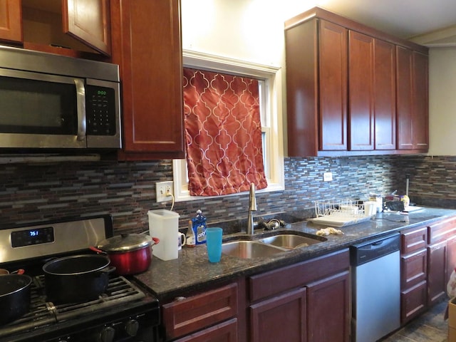 kitchen with decorative backsplash, stainless steel appliances, dark stone counters, and sink