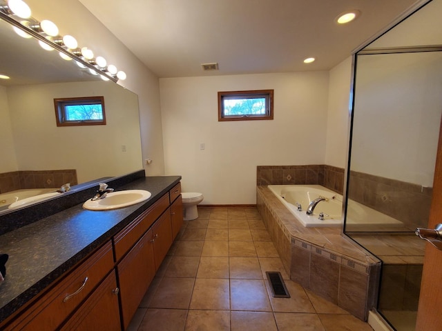 bathroom with toilet, vanity, tile patterned floors, and tiled bath